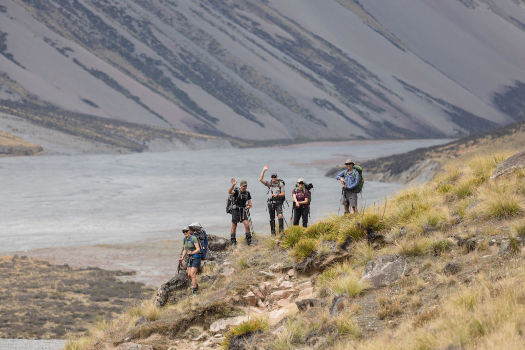 Hikers hight on a hillside with a braided river in the background