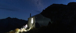 Mountain hut at night time, with stars and night sky in the background