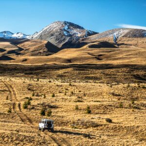 Braemar Station 4WD Tour - car crossing a farm track with snow-capped mountains in background