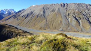 Looking down off a hillside into a river valley with mountains in the background, in New Zealand's Mackenzie Country